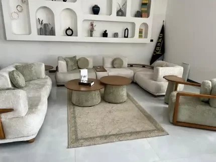 نمای زاویه‌دار مبل راحتی ۸ نفره ال کویین با ترکیب رنگ کرم و دسته‌های چوبی در دکور مینیمال