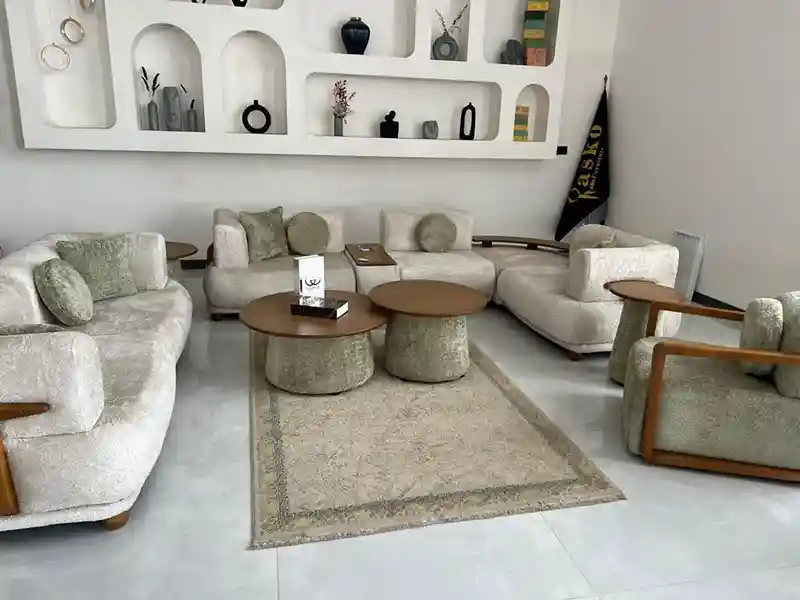 نمای زاویه‌دار مبل راحتی ۸ نفره ال کویین با ترکیب رنگ کرم و دسته‌های چوبی در دکور مینیمال